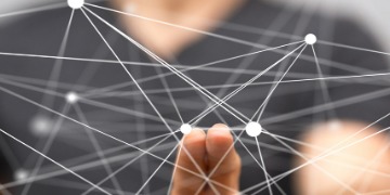 virtueller Unterricht Im Hintergrund ist ein Mensch sichtbar, der ein Netz aus Kreisen im Vordergrund mit seinen Fingern beeinflusst.
